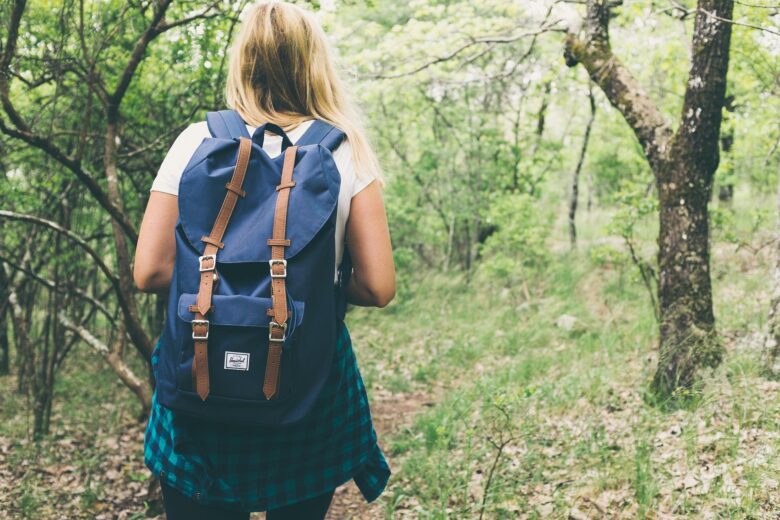girl with backpack hiking in woods